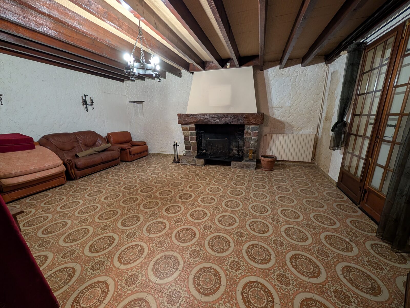 Salon avec carrelage à motifs, cheminée et poutres